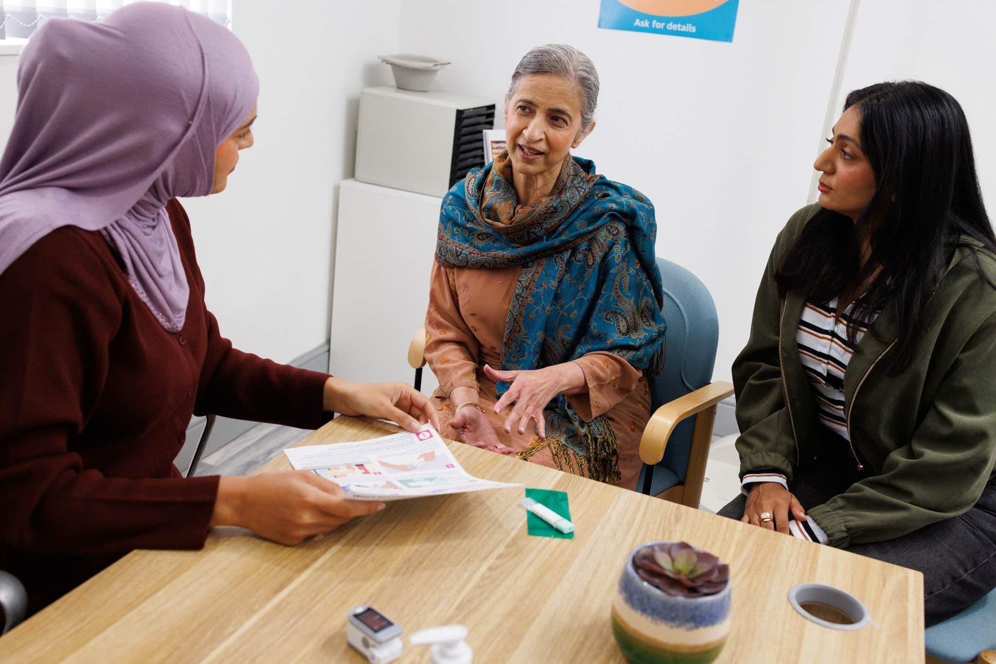 Doctor at the GP surgery talking to the patient and her carer.