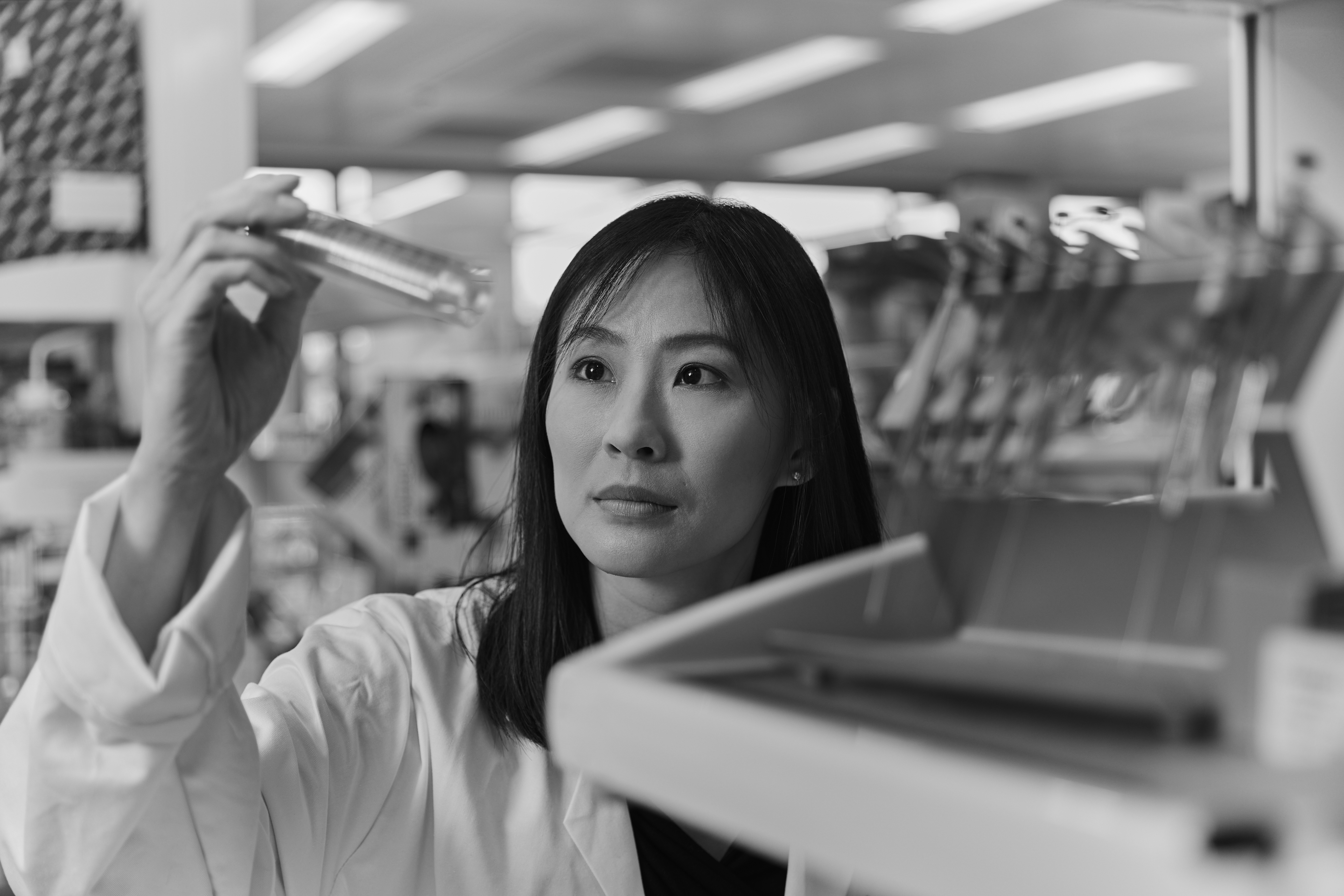 Researcher Vivian Li, working in a laboratory and looking at a test tube.