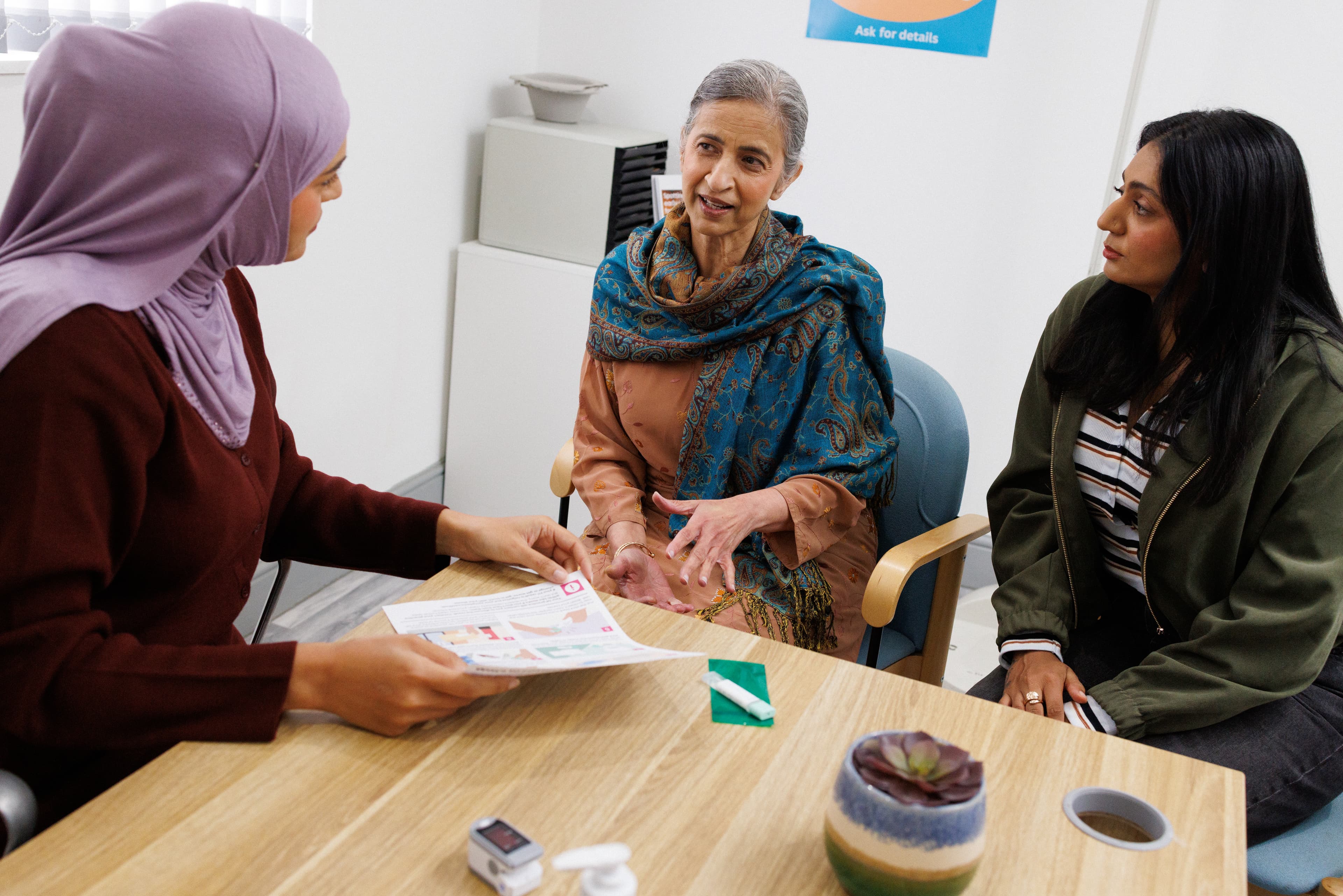 Doctor at the GP surgery talking to the patient and her carer.