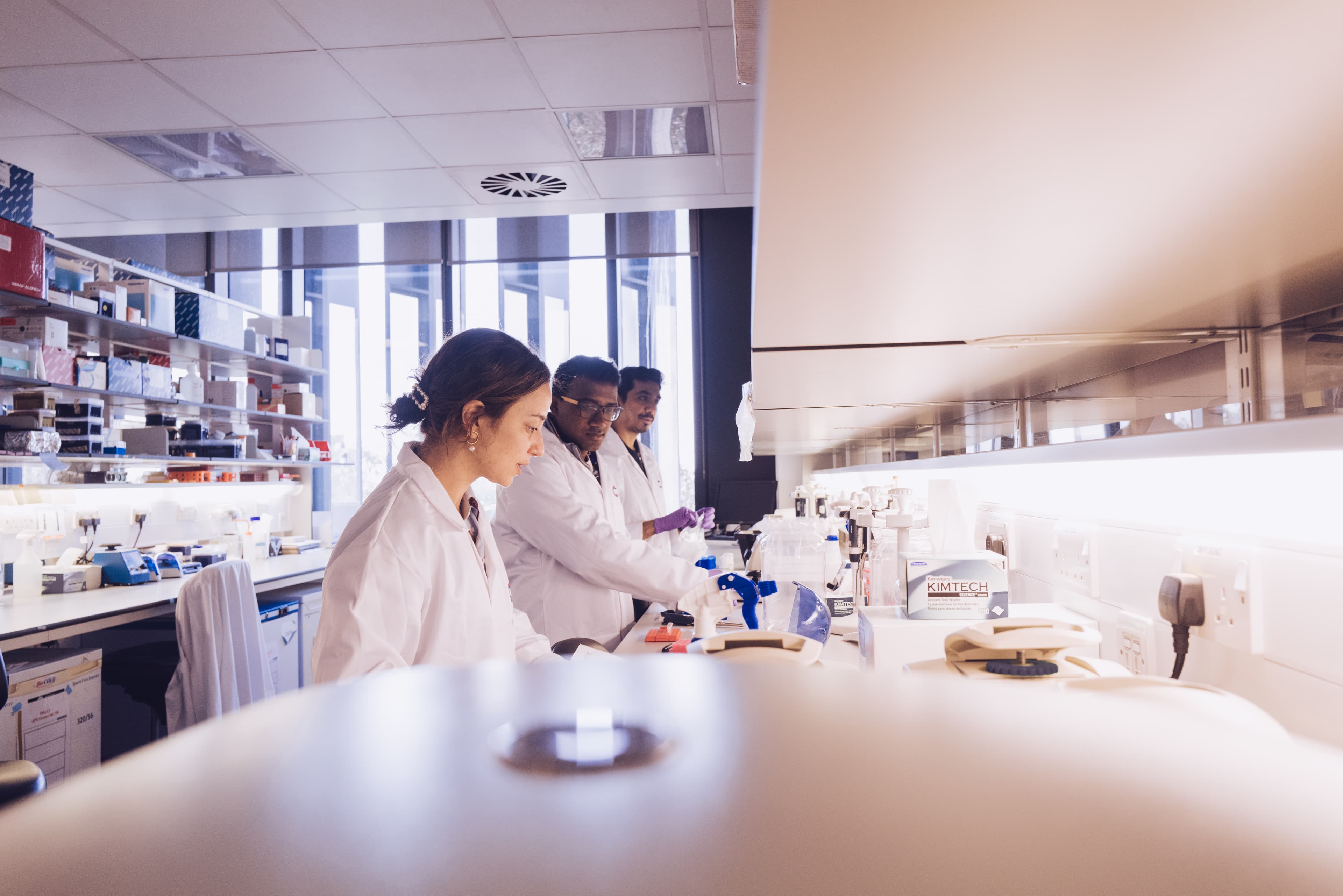 Three researchers wearing Cancer Research UK branded lab coats.
