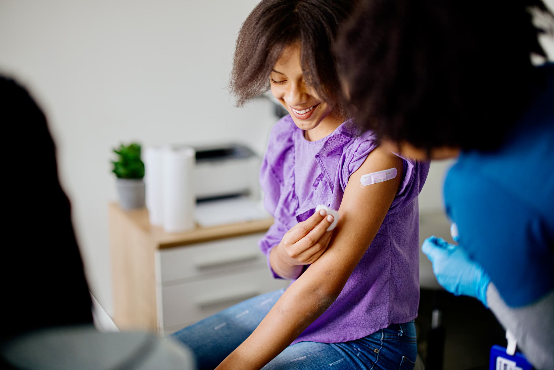 Image of a young girl getting the HPV vaccine. She looks at ease and happy.