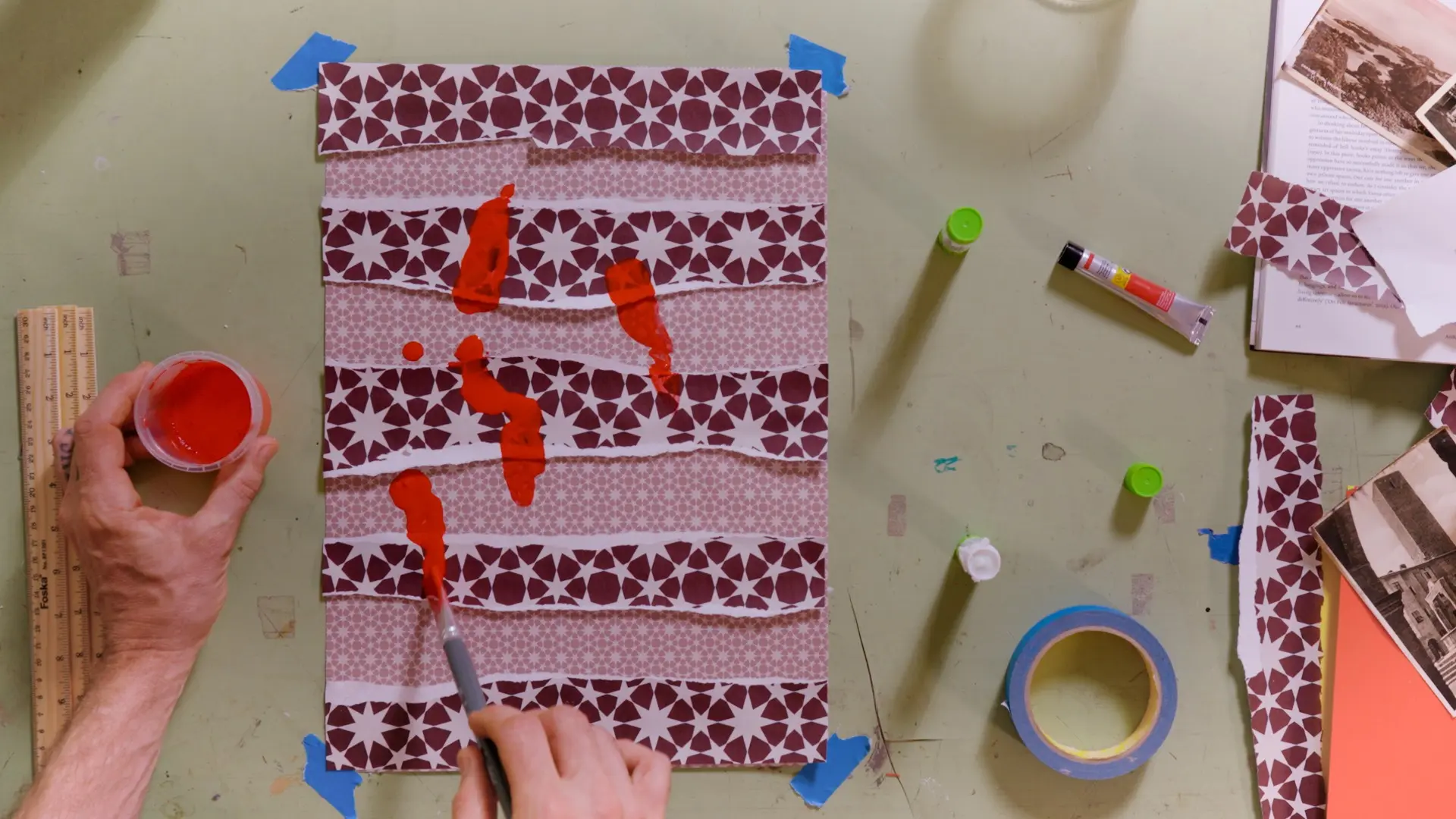 Photo of an artist holding a paintbrush while creating a piece of abstract work.
