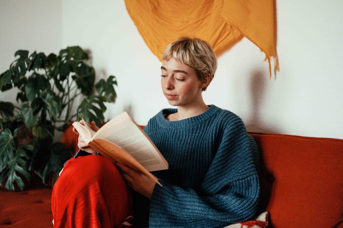 Photo of a person on the sofa reading a book.