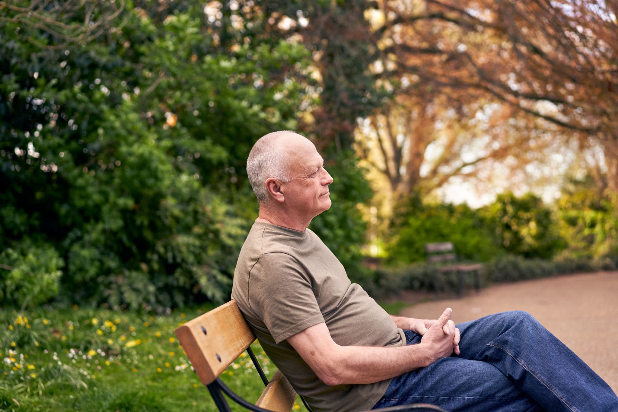 Photograph showing a man sitting on a park bench.