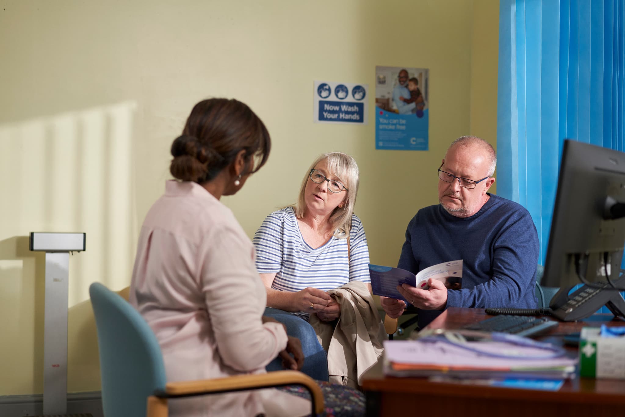 Photograph showing a doctor sitting with a couple.