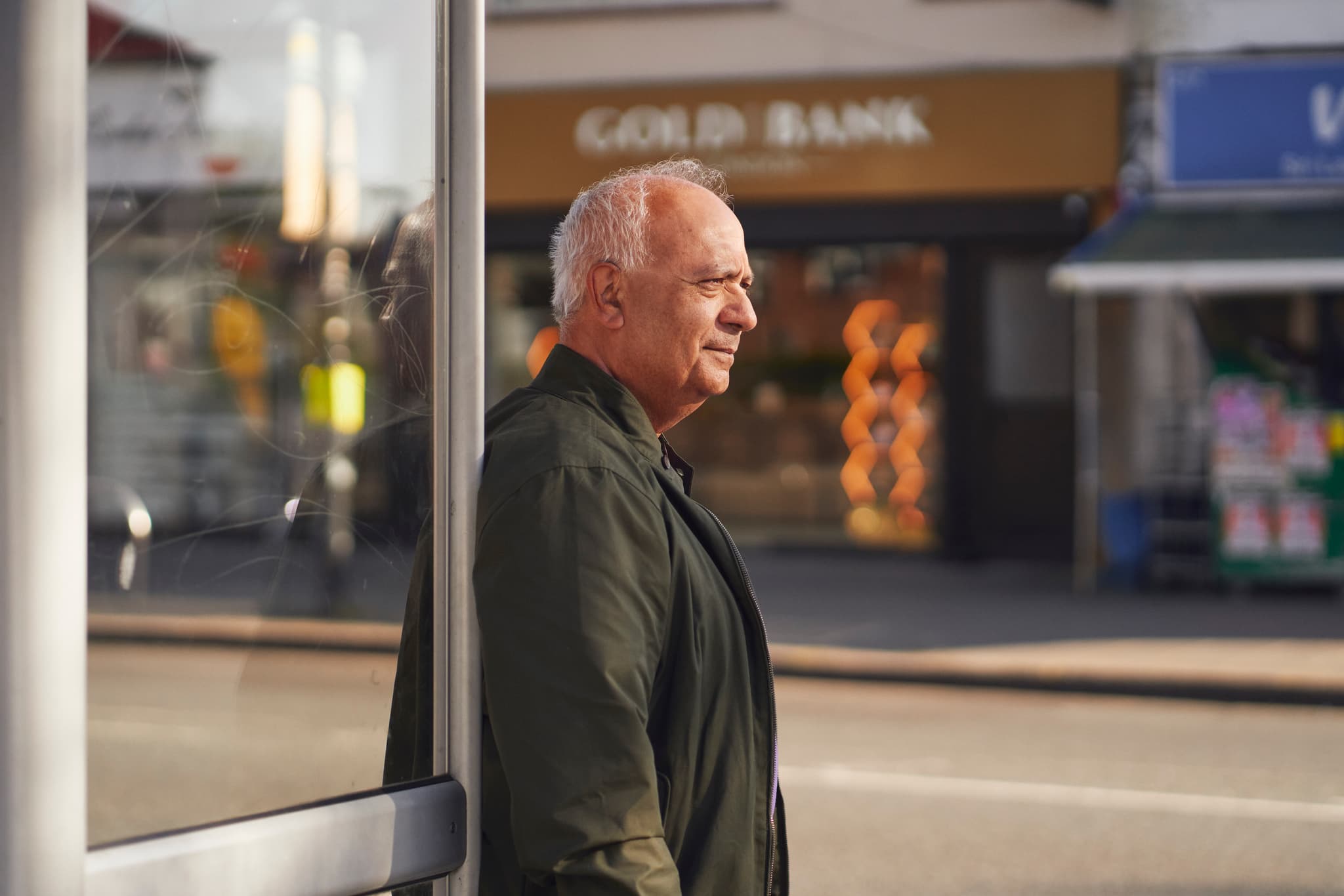 Photograph showing a man waiting at a bus stop.