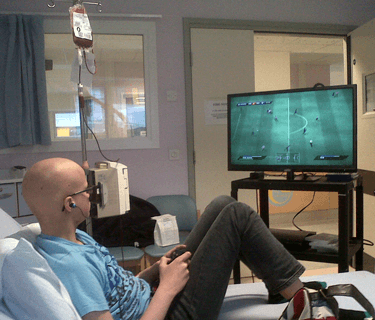 Young person with cancer playing a games console.
