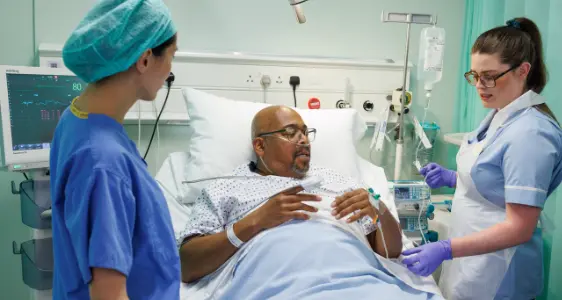 Photo of a man with anaesthetist and nurse after surgery.