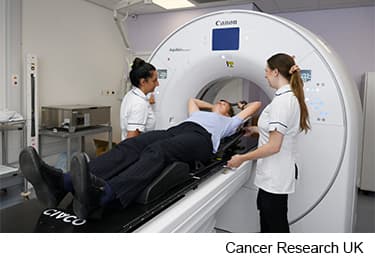 Photo of a women having a CT scan with a breast board.