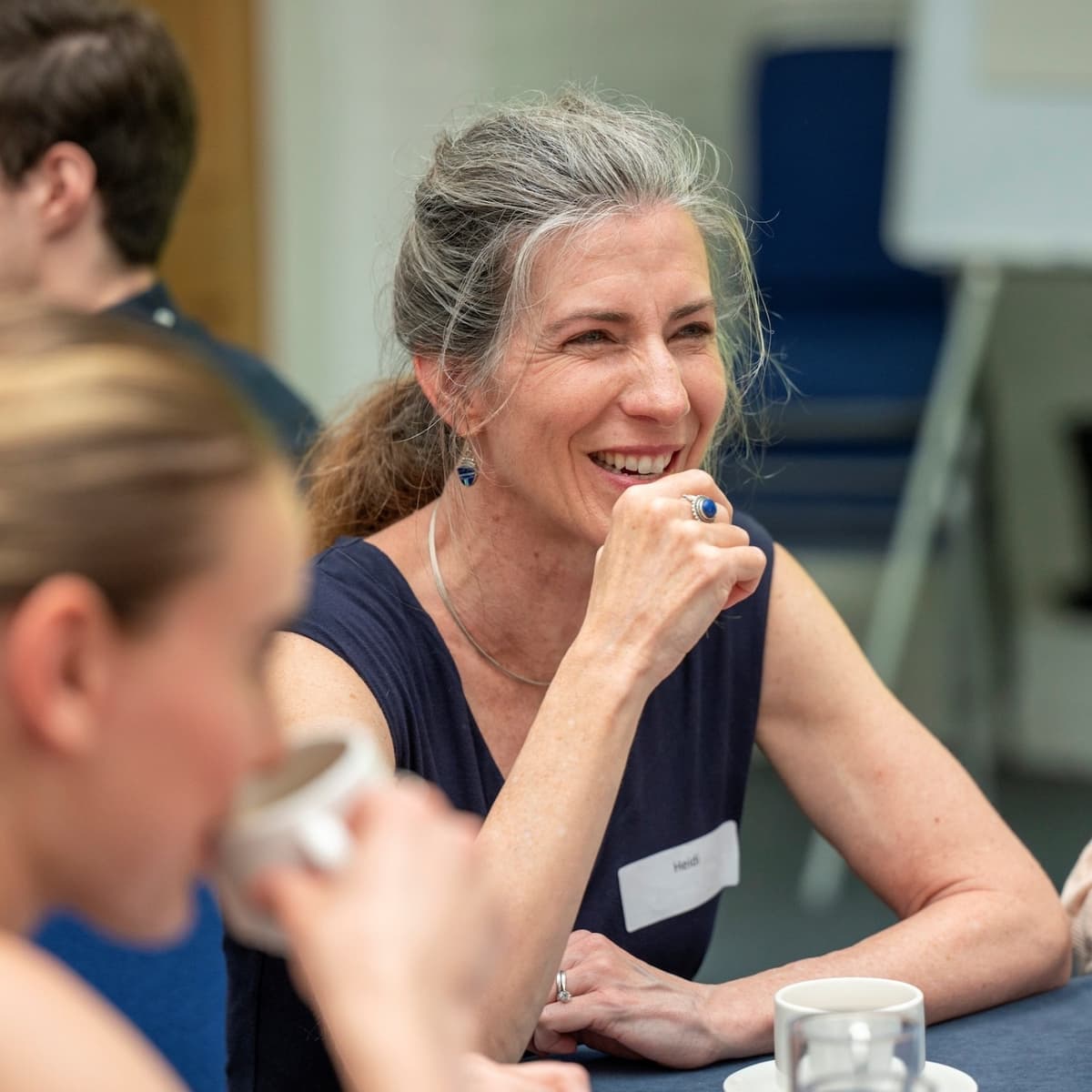 Smiling woman sat at a table with others at an event.