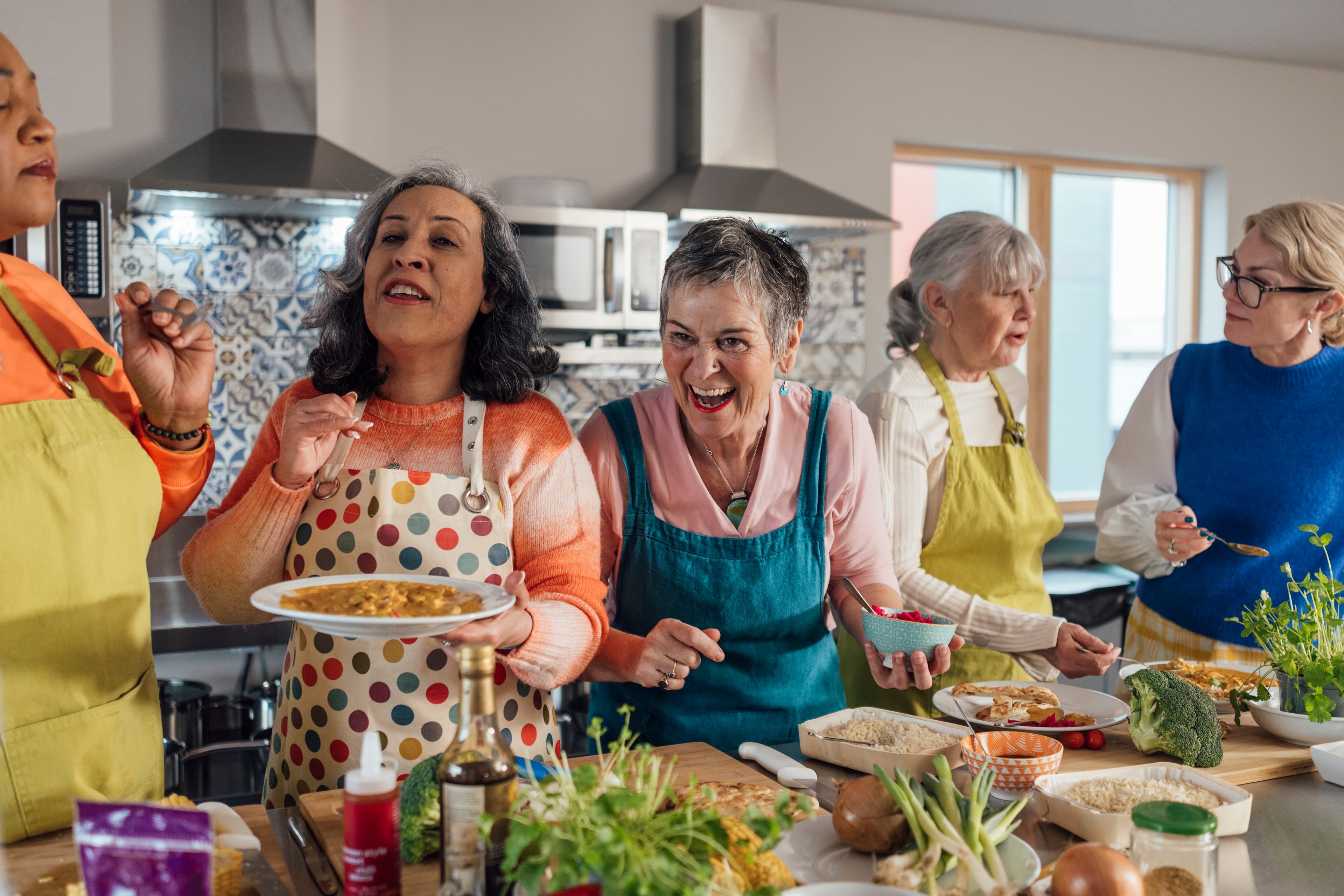 A group of mature and senior women enjoying a staycation and taking part in a cooking class in Amble, North East England.