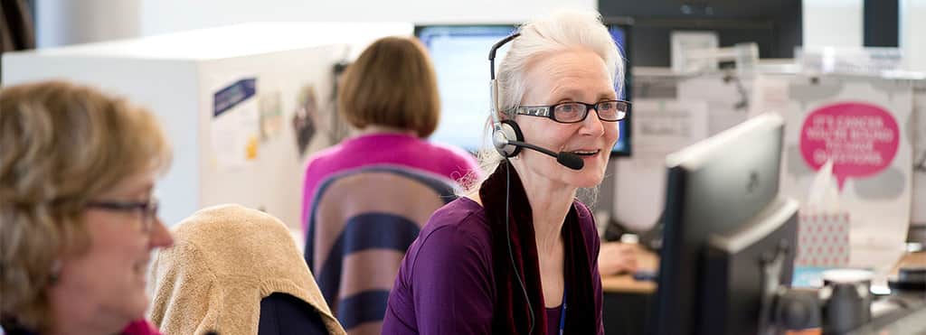 Helpdesk worker at computer, using headset.