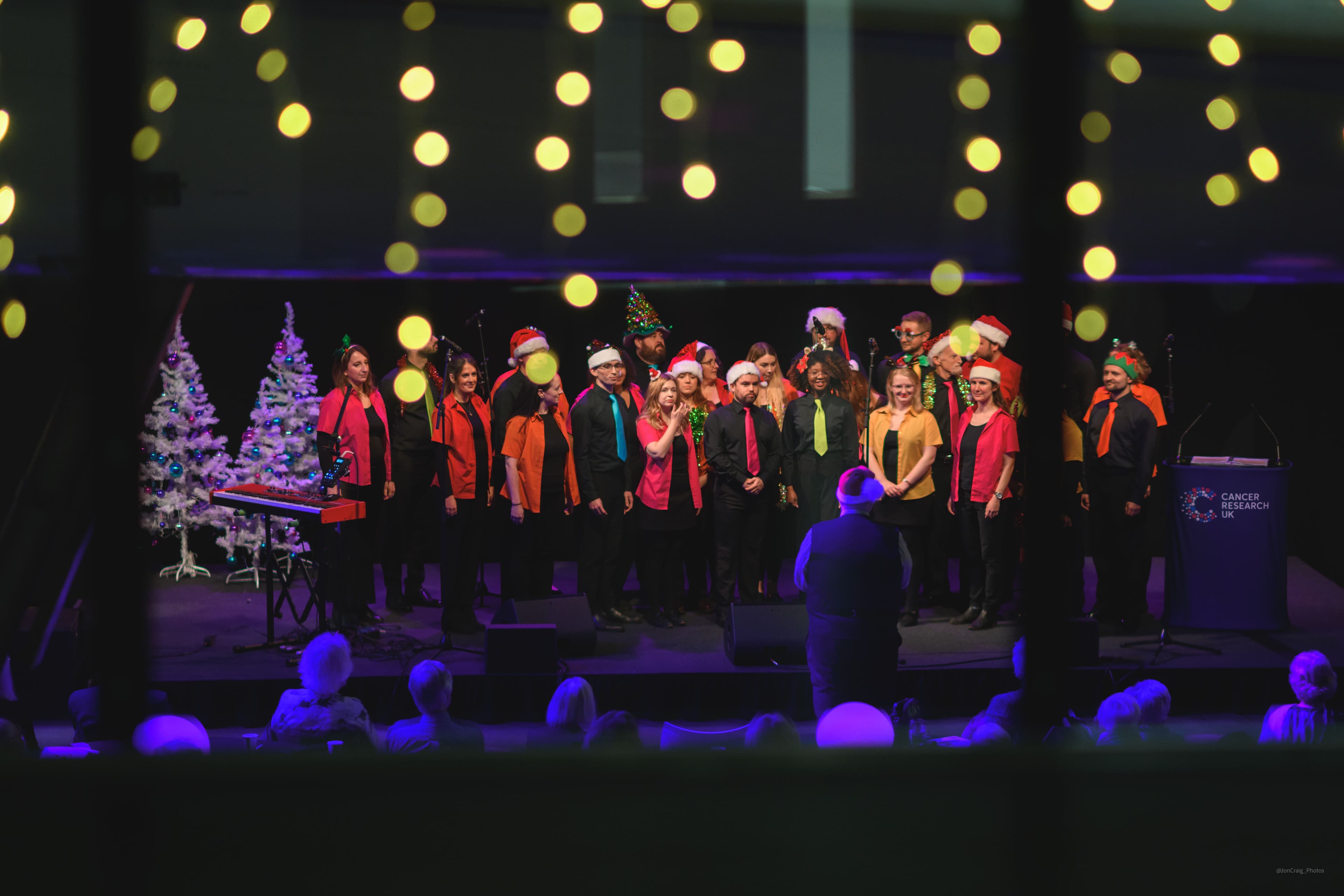 Carol singers wearing festive hats, singing at a Legacy Festive Music event.