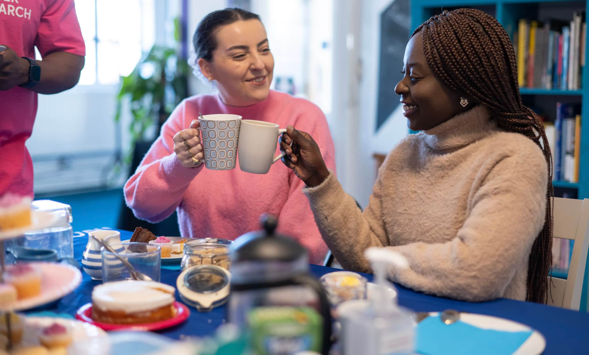 Image of two women smiling and drinking coffee together.