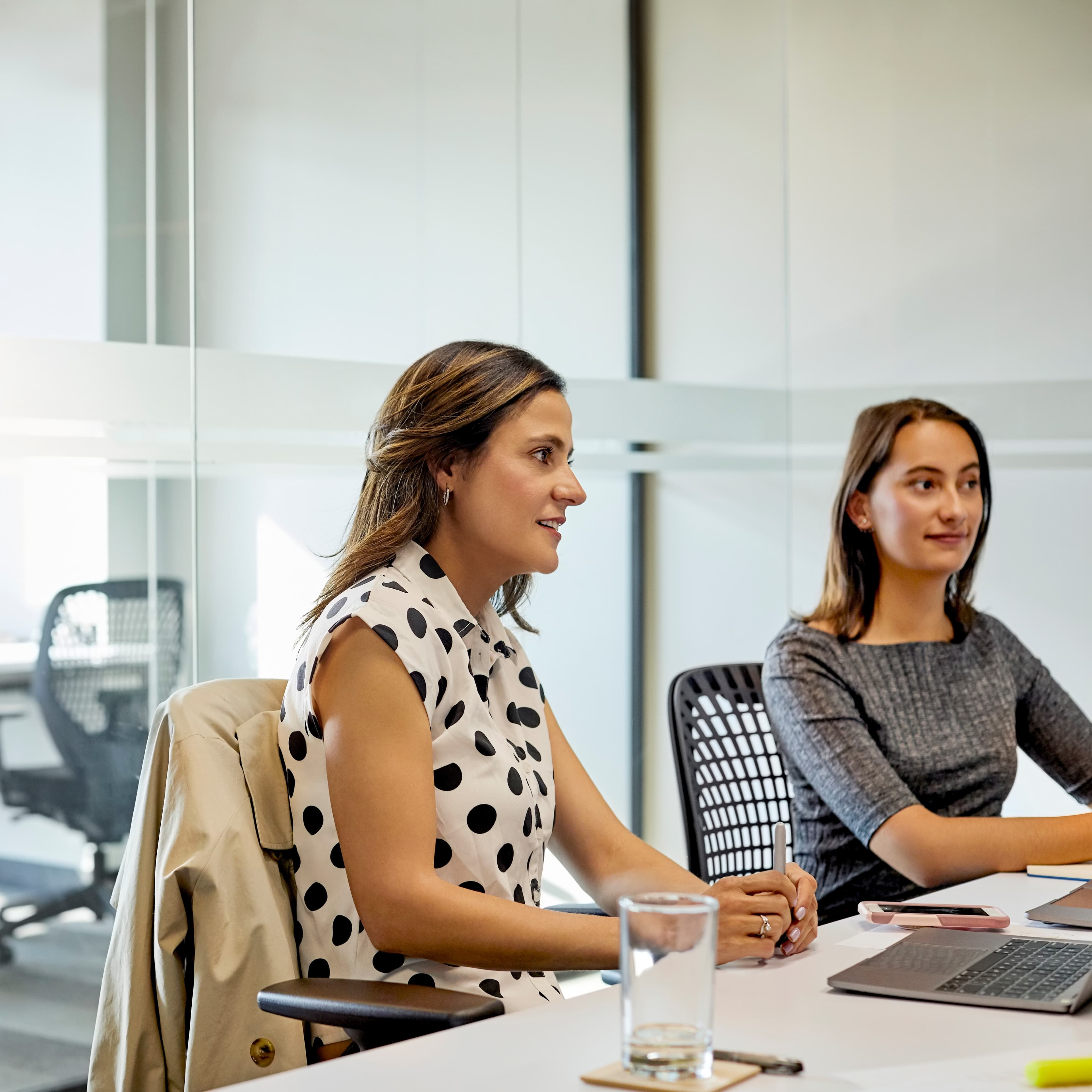 Two women sat at a desk in a business meeting.