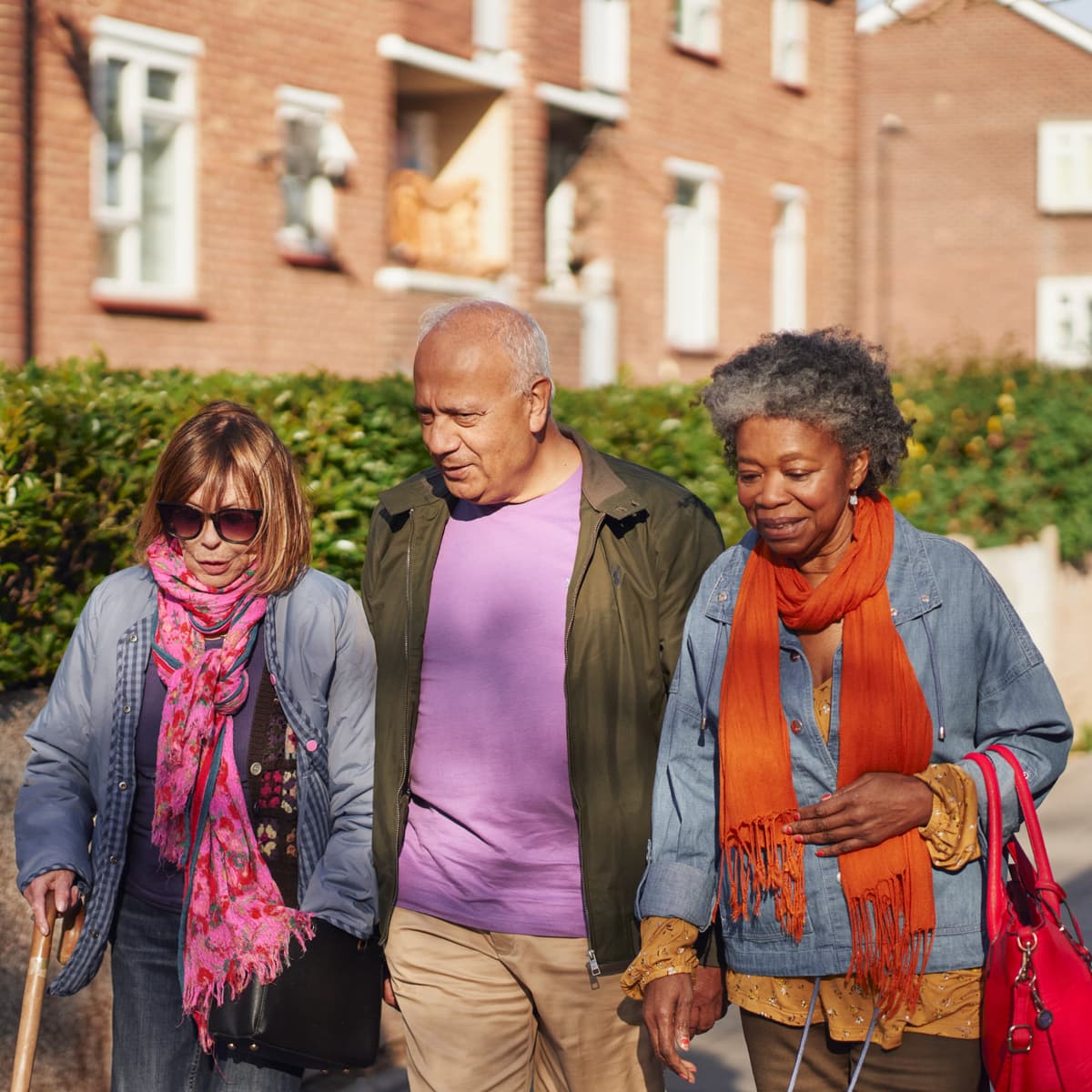 Three people walking down the street chatting to each other.