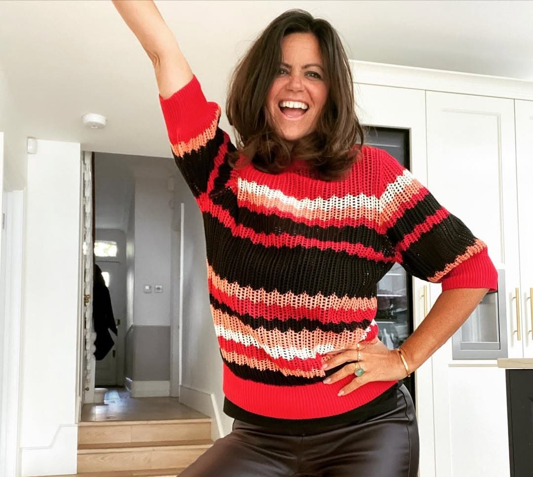 Image of Dame Deborah James smiling with one hand on her hips and her other hand in the air.