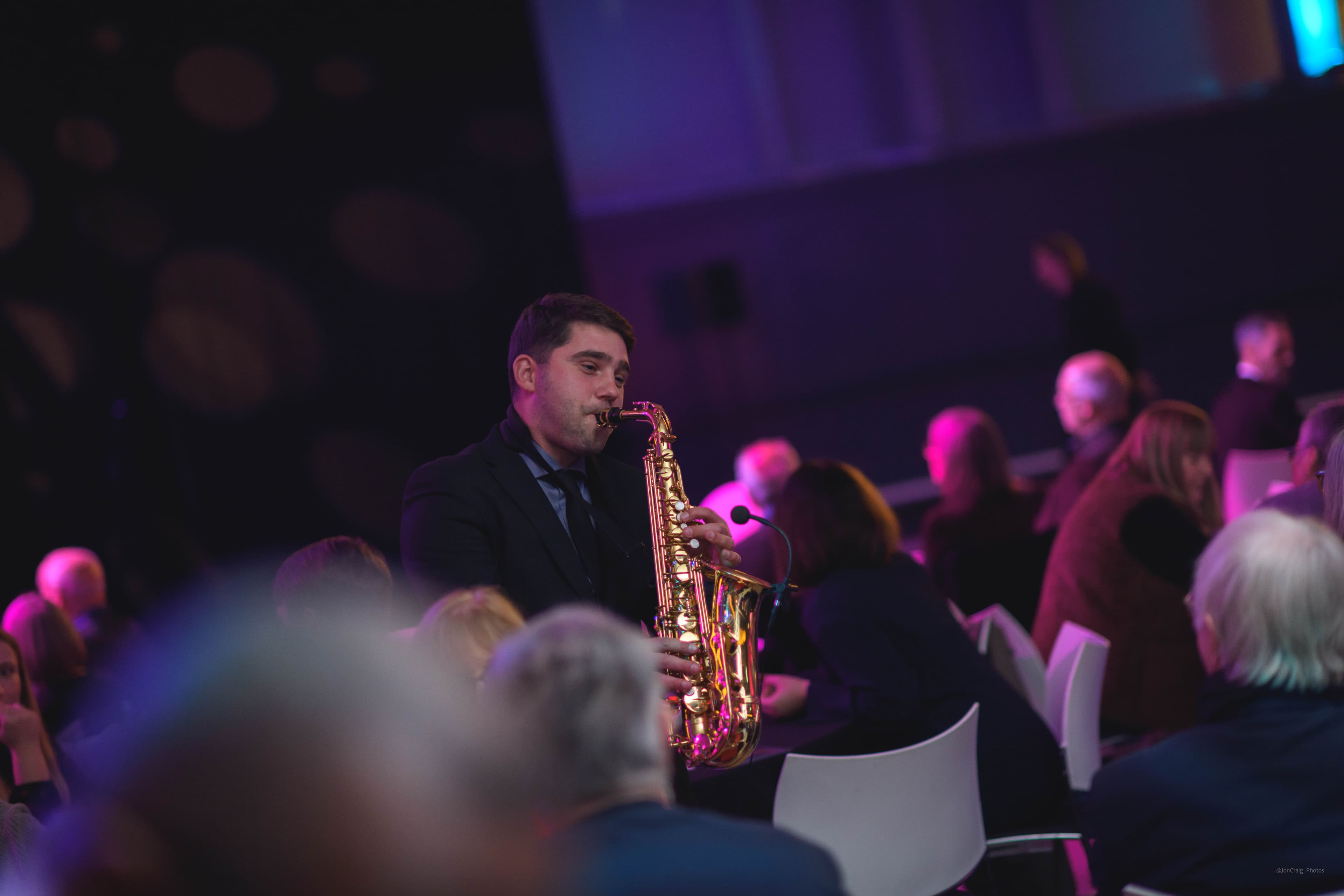 Musician playing a saxophone at a Legacy Festive Music event.