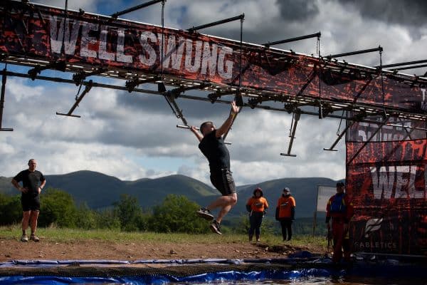 Event participant on a swing obstacle above water.