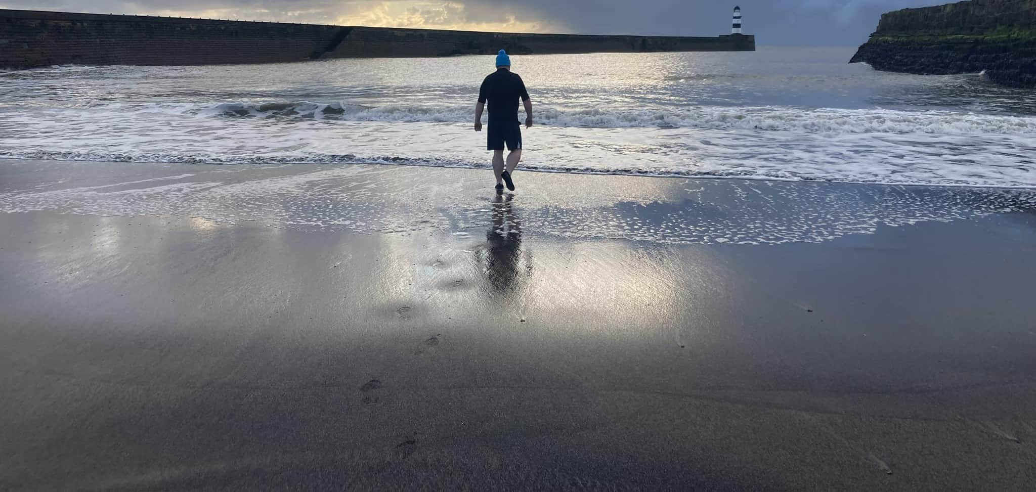 Picture of a man walking into the sea.