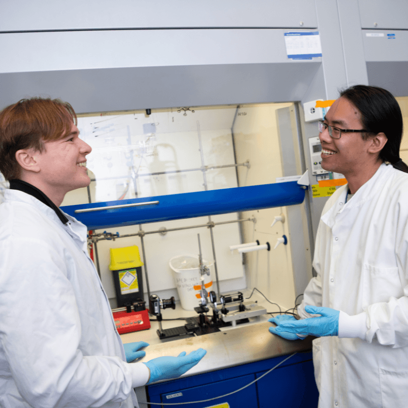 Two researchers in lab, smiling.