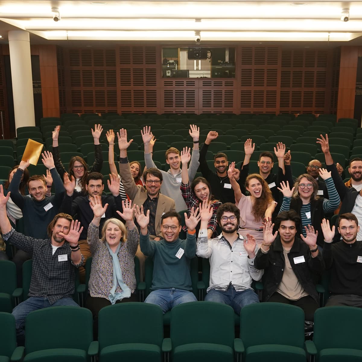 People sitting in a conference hall, taking a group photo.