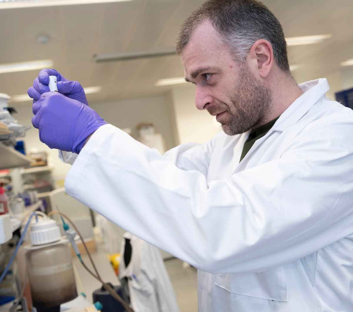 Image of a male scientist in a lab coat checking research equipment.