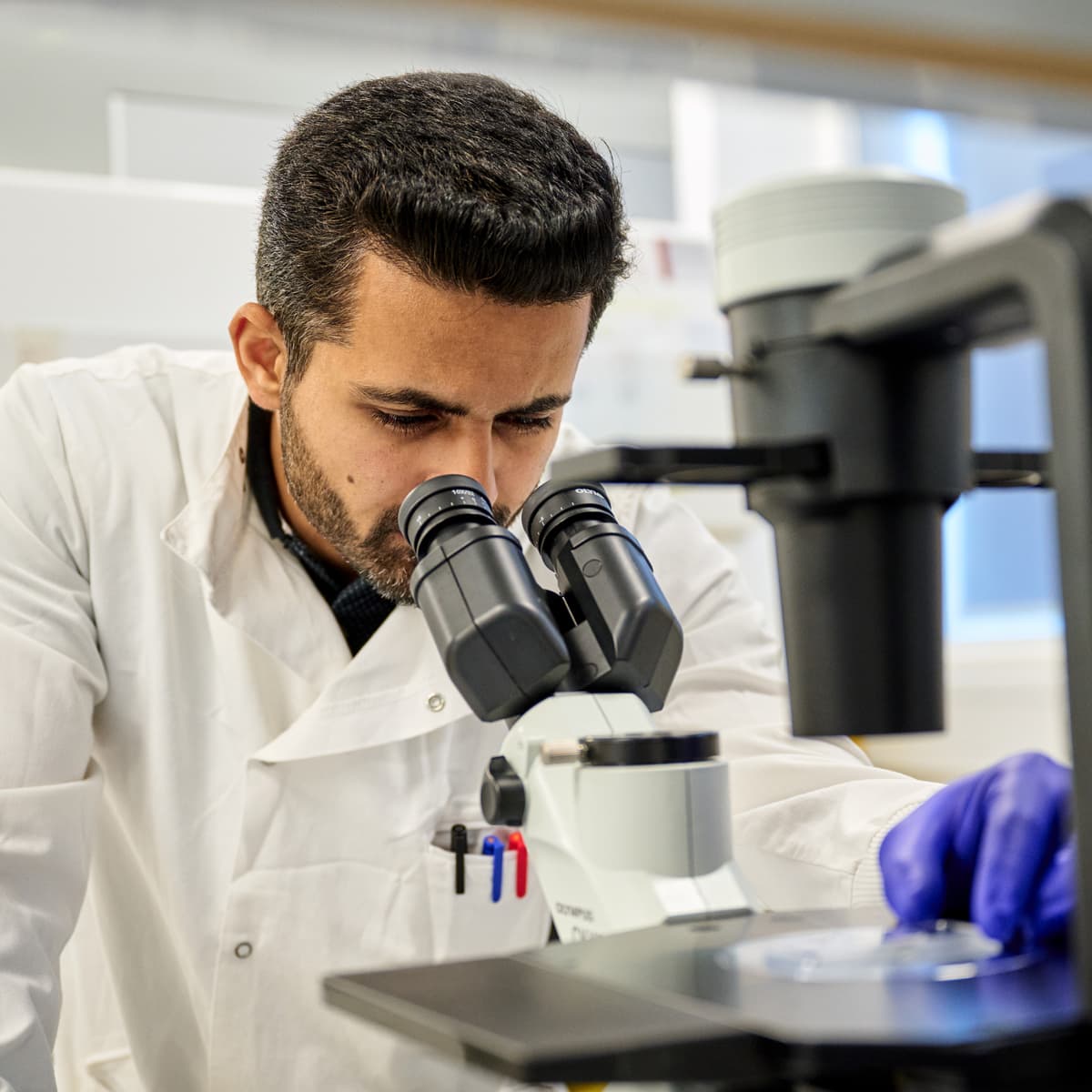 A scientist looking down a microscope.