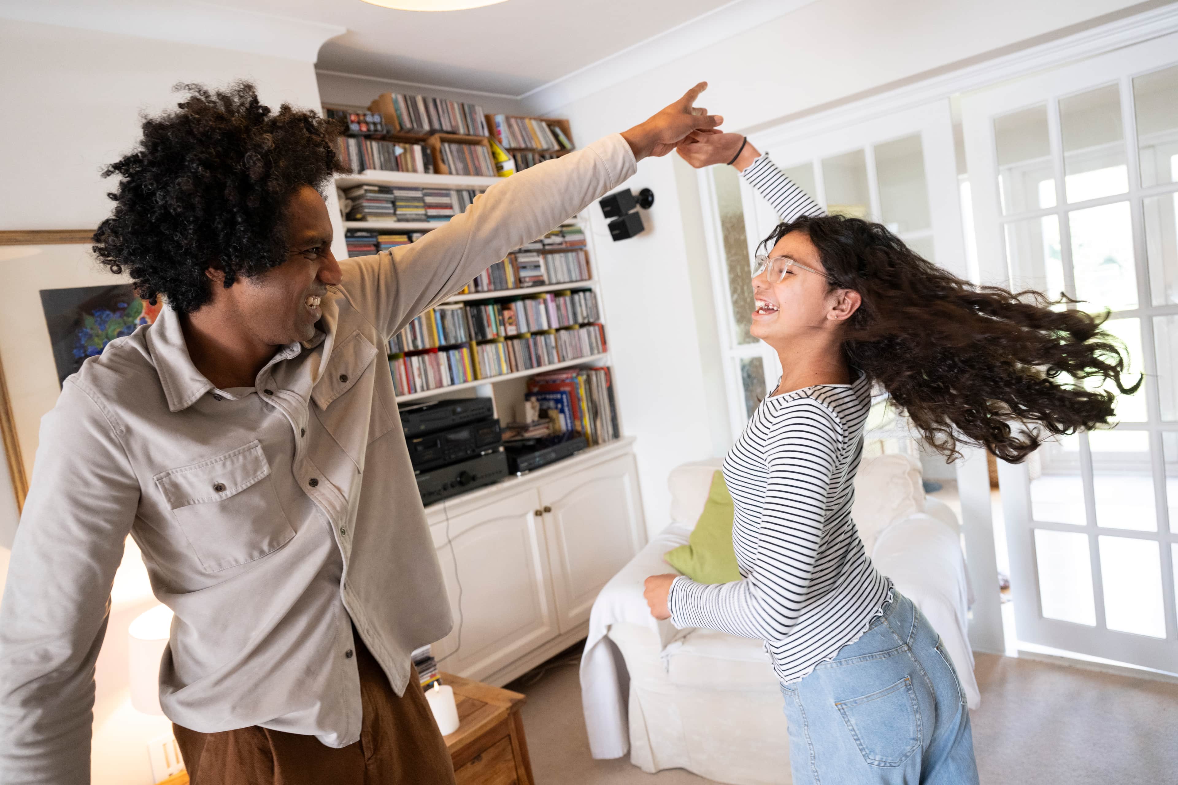 Two people dancing in a bright living room, one twirling the other.