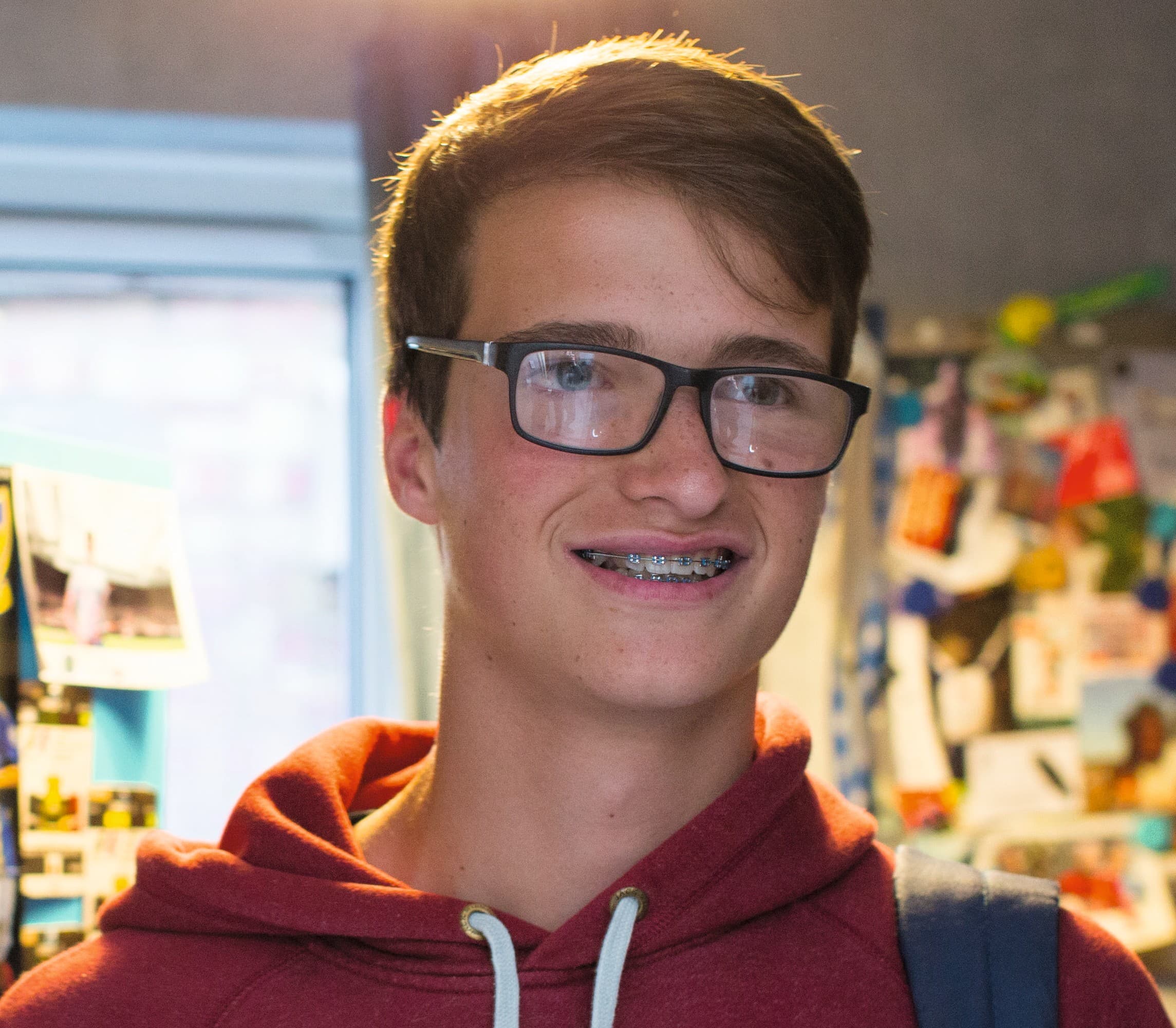Adam, in remission from non-Hodgkin lymphoma, is standing in front of boards with photos, smiling.