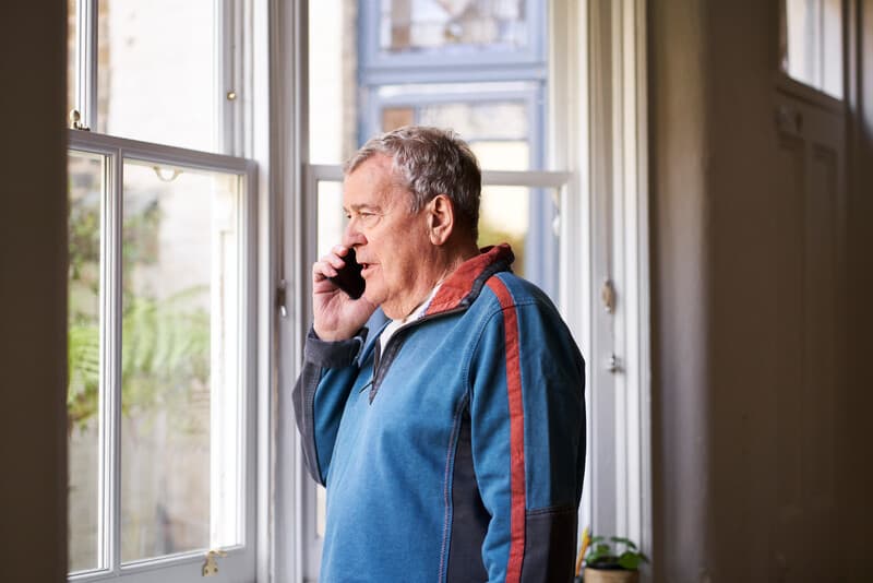 Man at window using mobile phone.