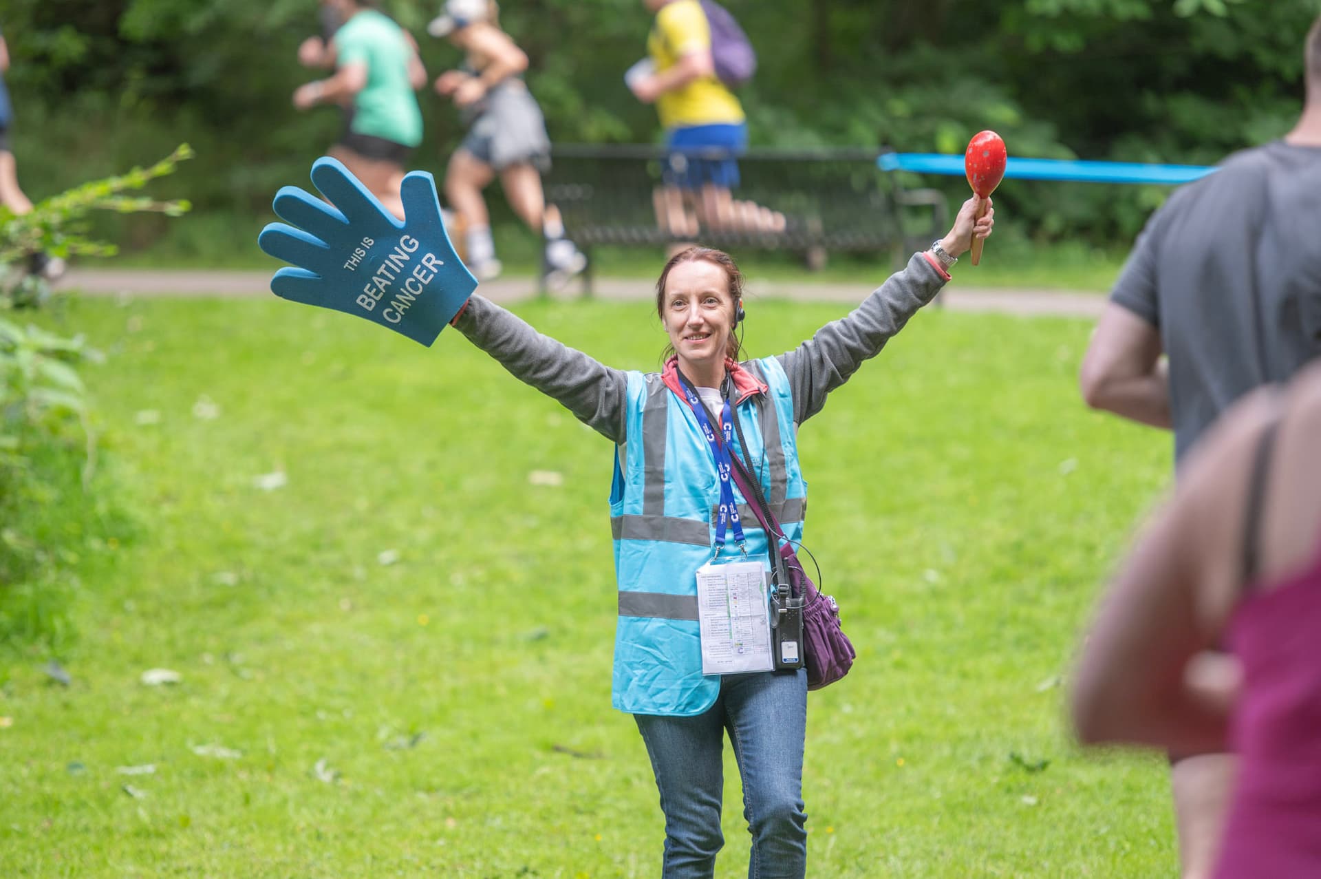 A female volunteer at an event wearing a high-vis vest and waving.