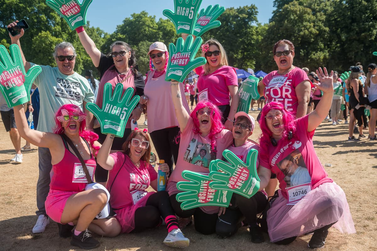 A group of people smiling and waving signs at a Race for Life event.