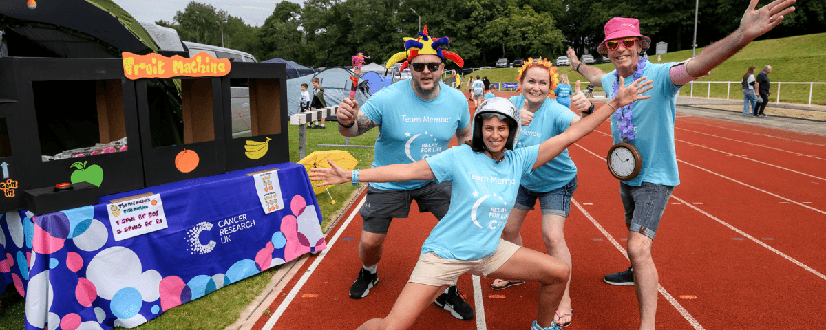 Four Relay For Life participants wearing costume hats, posing on the track.