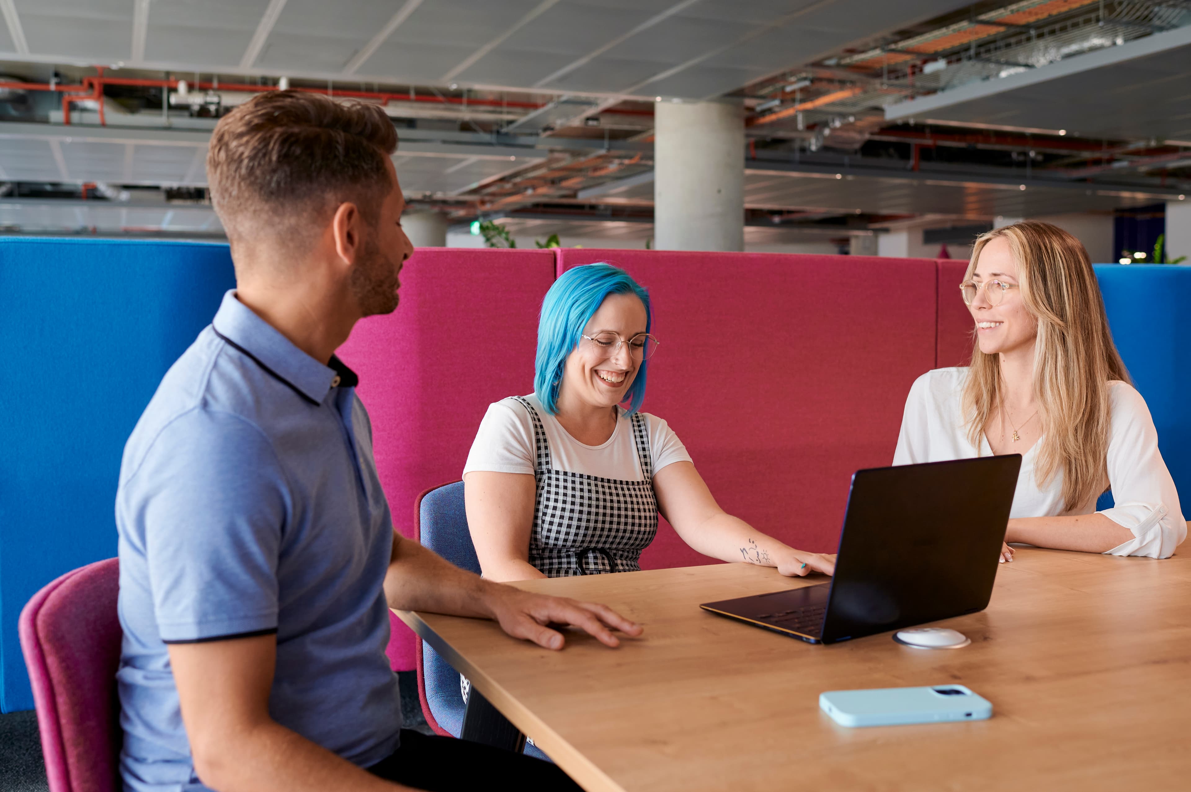 Photo of three Cancer Research UK staff members sat in a bright office having a conversation.