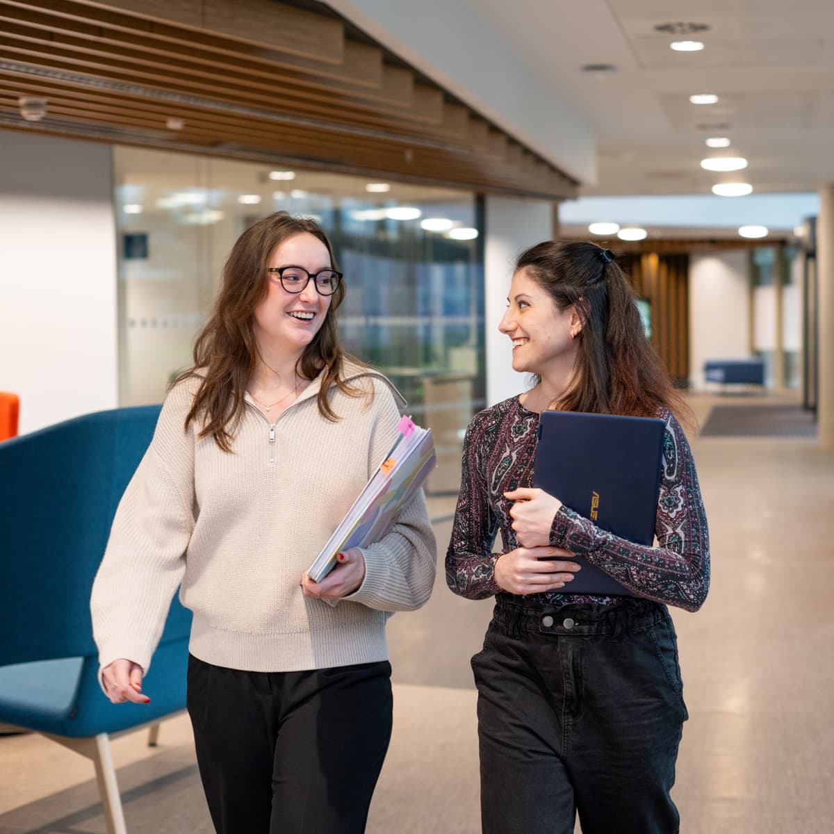 Image of two researchers working in a lab, holding lab equipment.