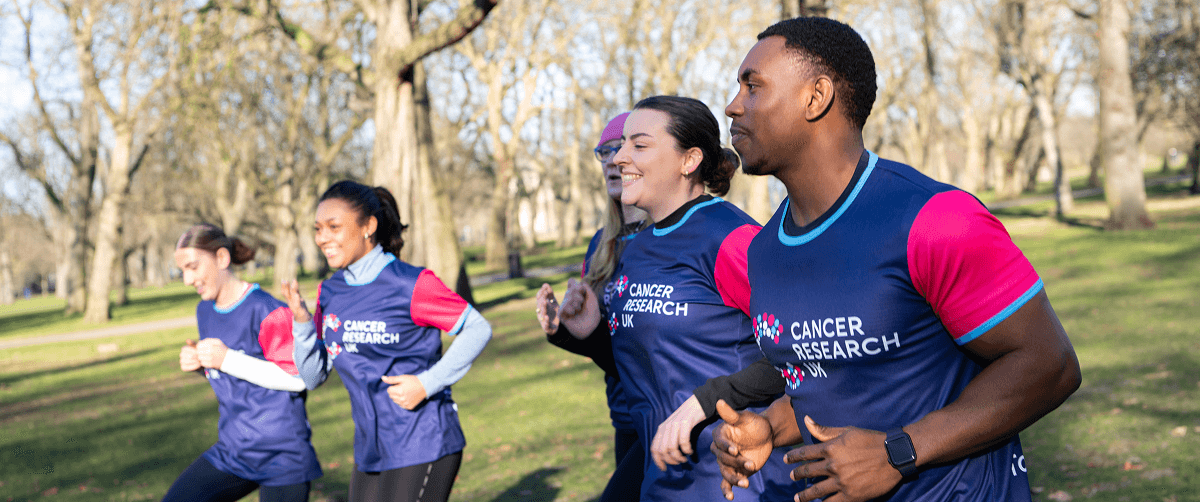 Group of people with CRUK T-shirts doing sports in a park.