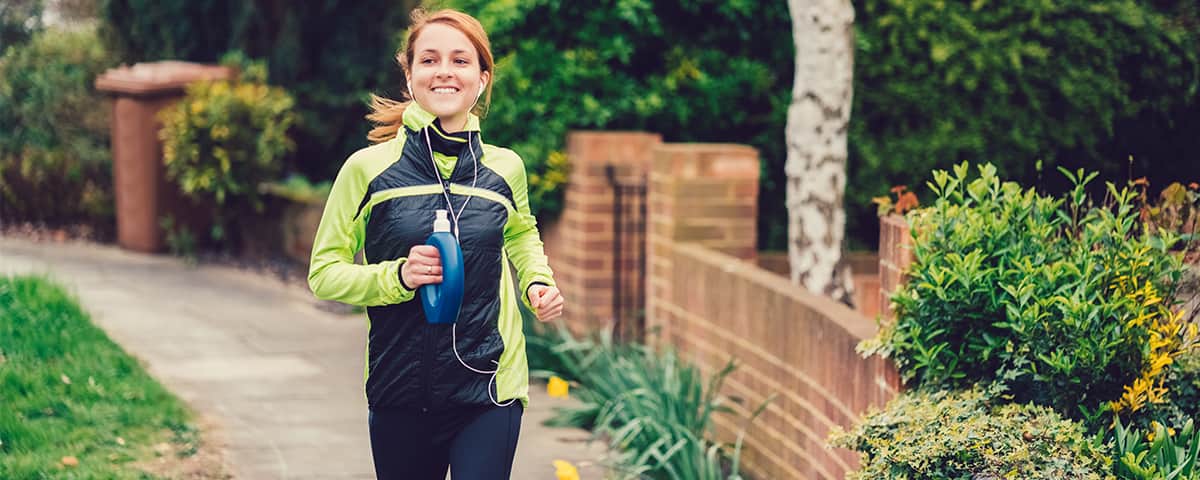 Woman running along the street smiling.