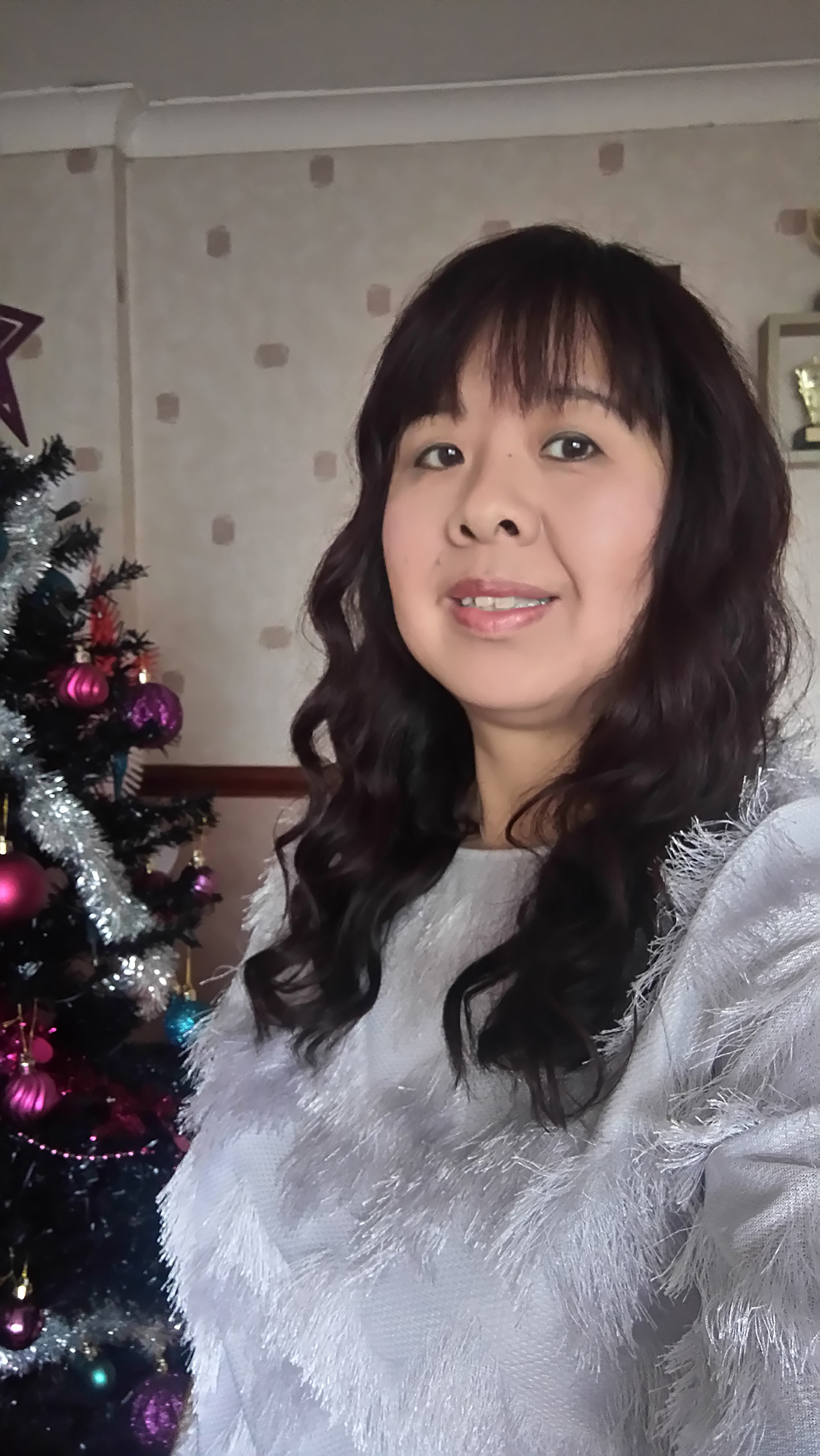 Jennifer, free from lung cancer since December 2013, smiling next to a Christmas tree.