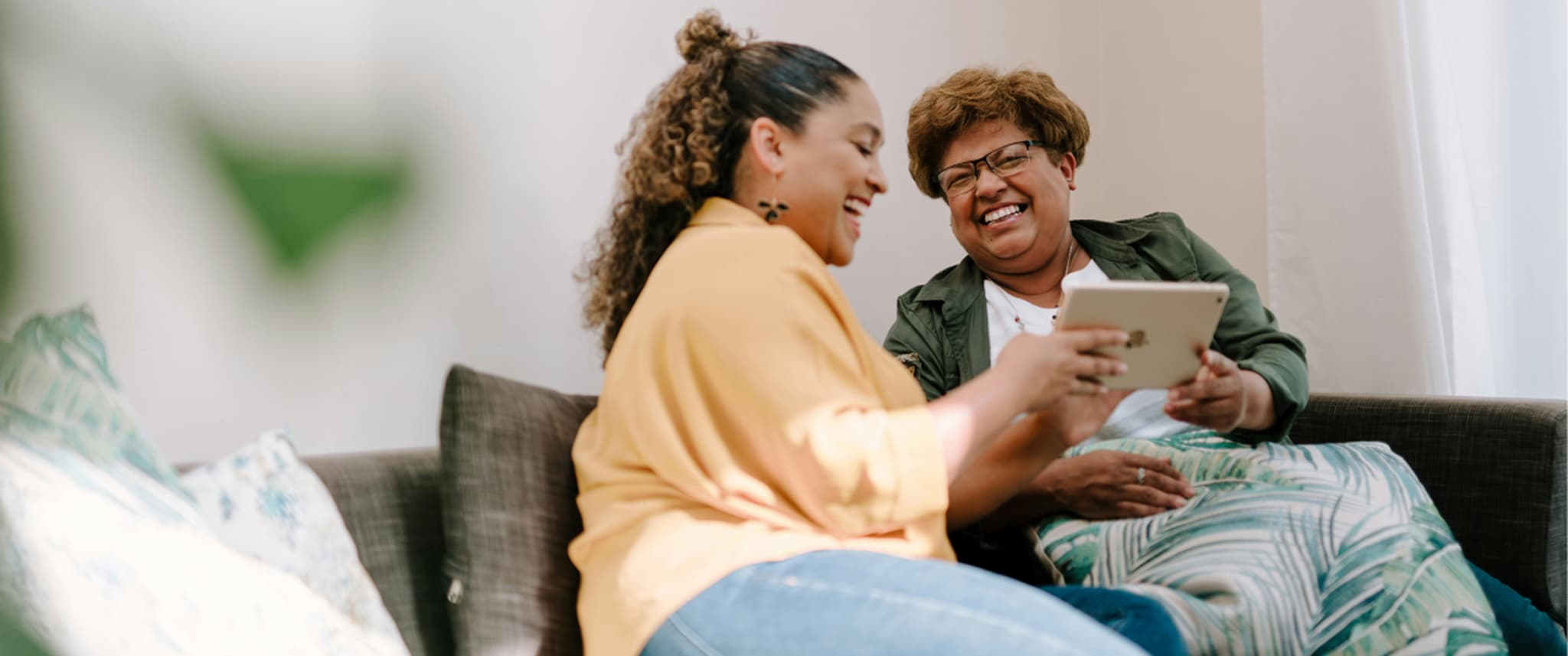 Two women laughing on the sofa.