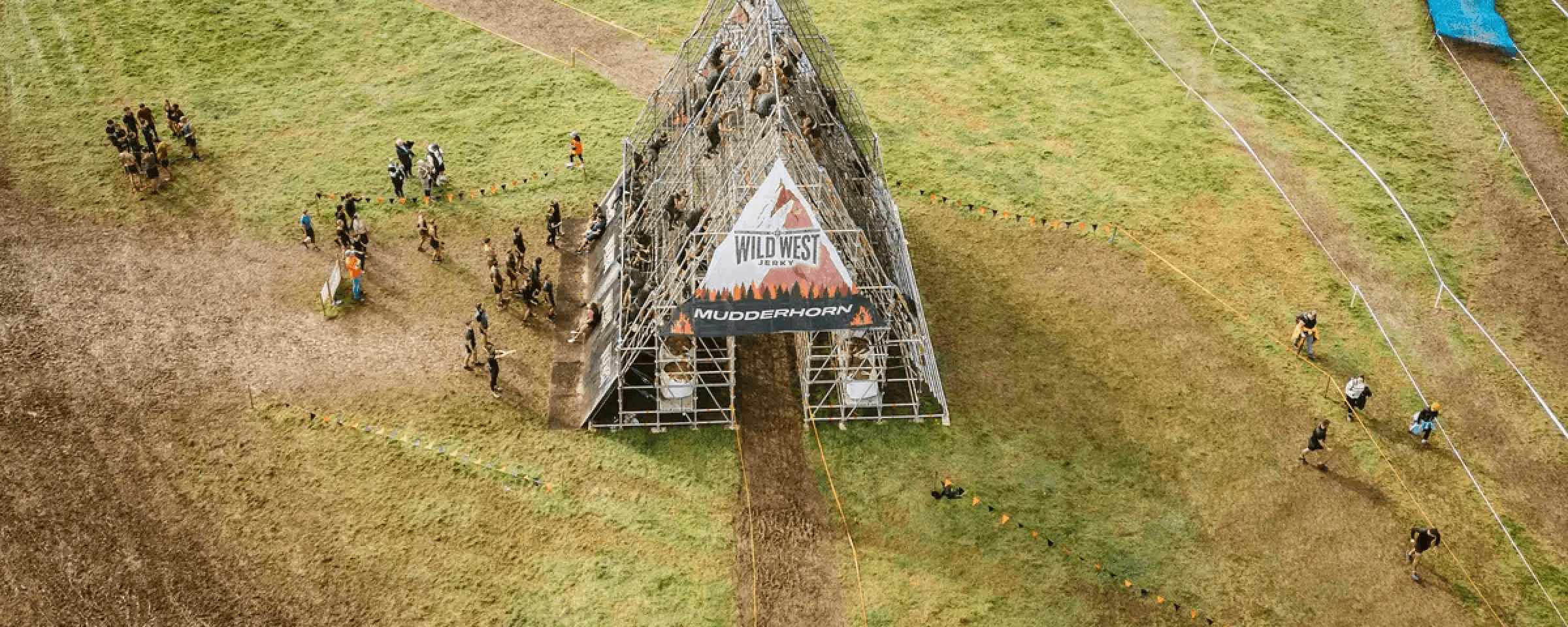 A photo of people in the middle of a green field climbing up and going down a metal house shaped structure.