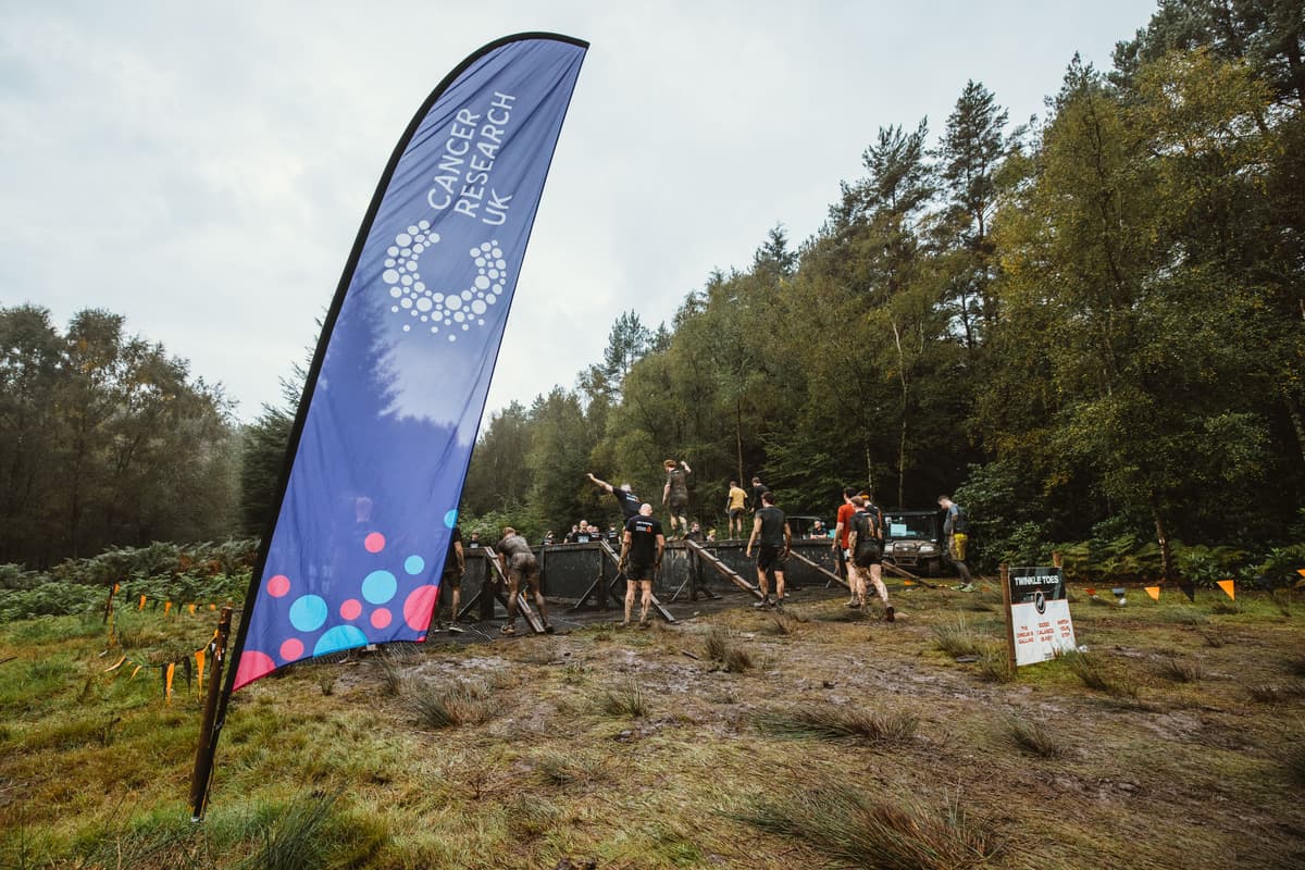 Cancer Research UK banner at Tough Mudder event in field.