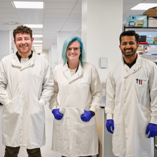 Three researchers smiling to camera.