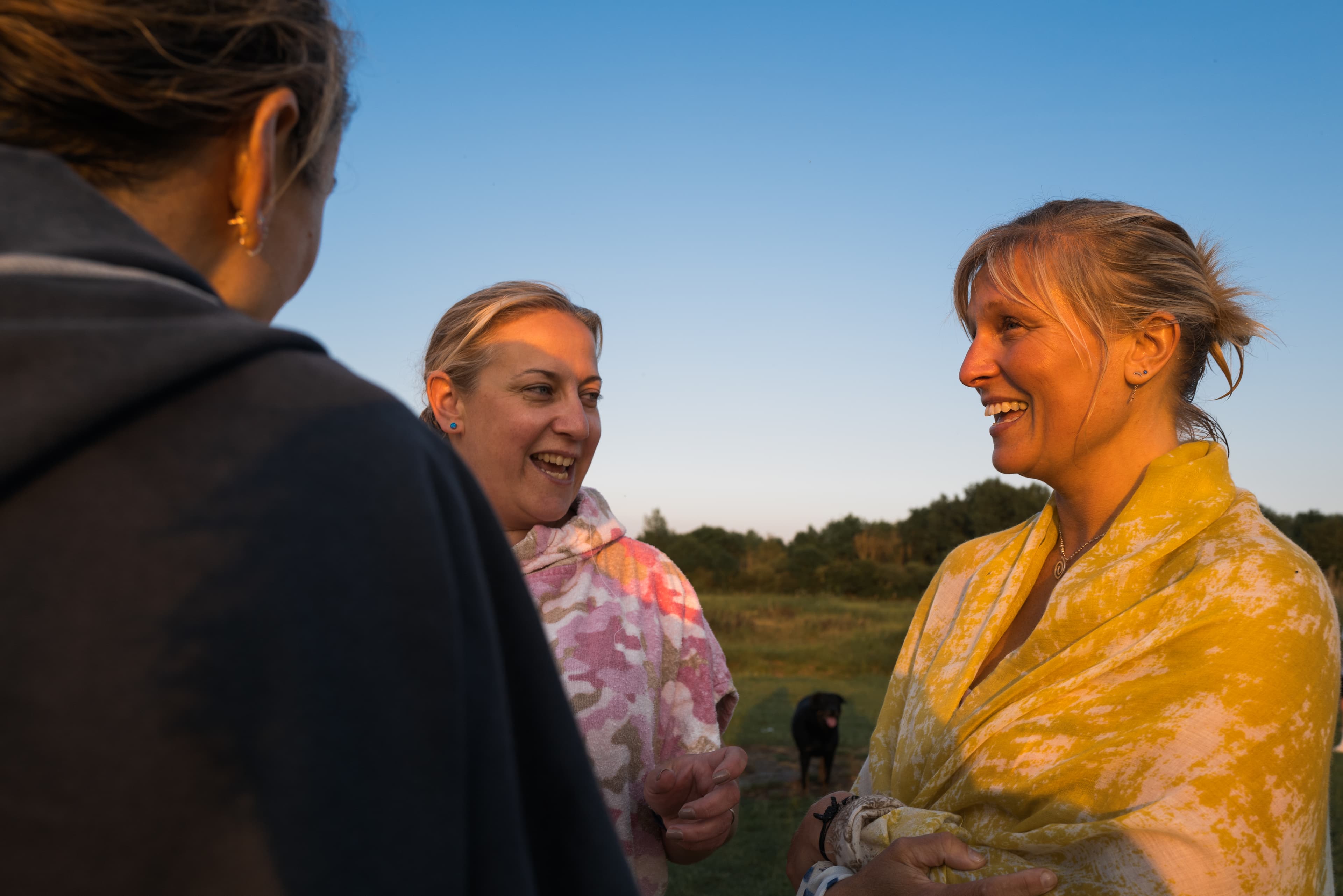 Picture of three women chatting outside, one is wearing a towel around her.