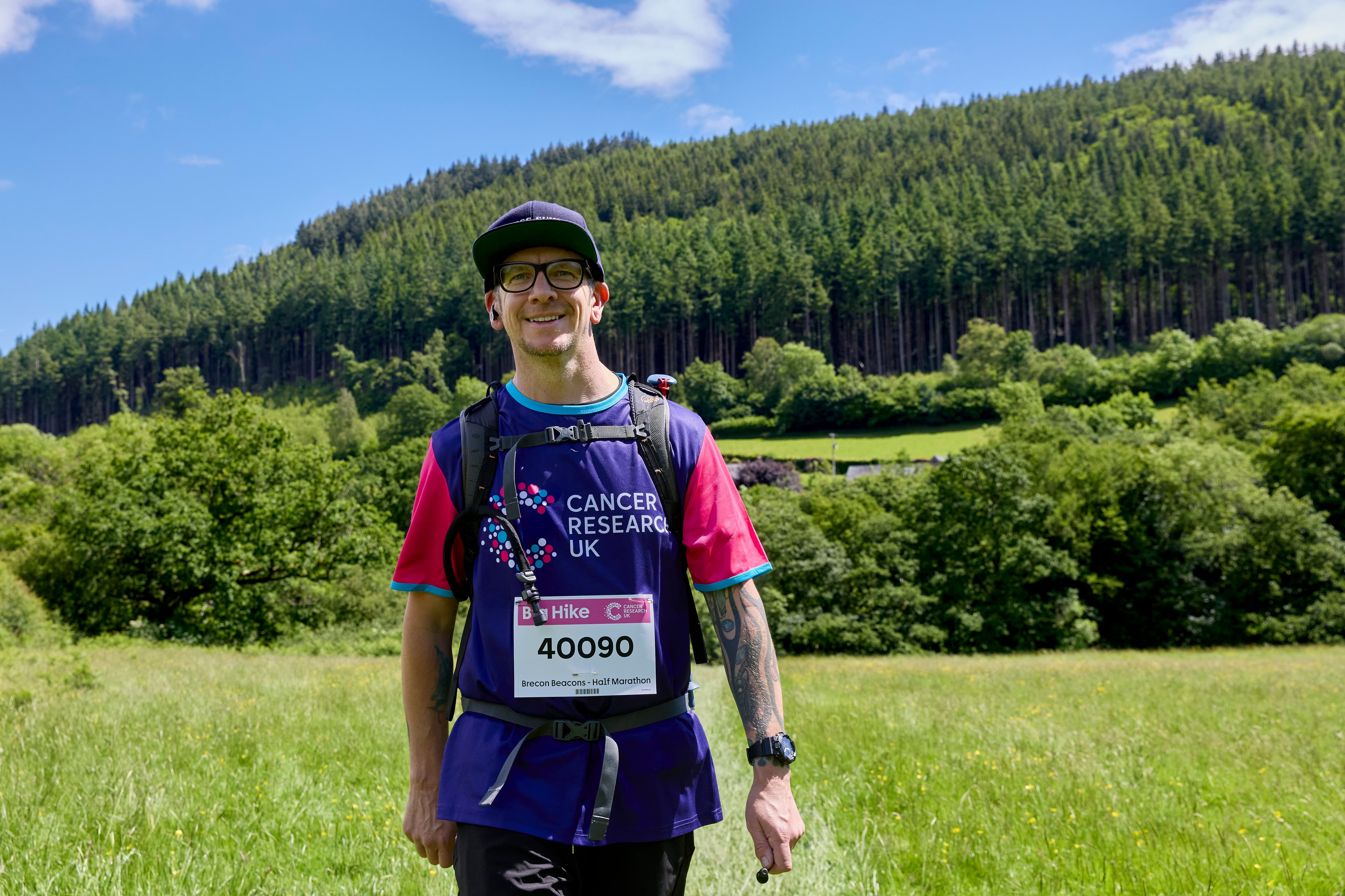 A Big Hike participant posing for a photo with trees and a field behind him.