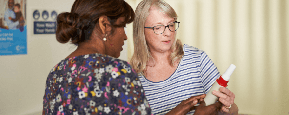 Image of two women looking at a bottle in a doctors office.
