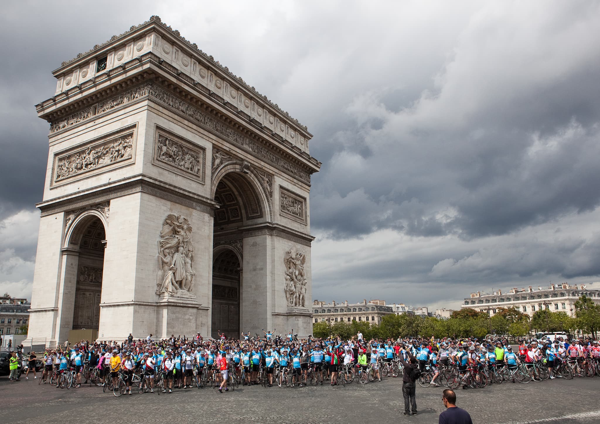 An image of hundreds of London to Paris Cycle participants, with bikes, in front of the Arch de Triomphe in Paris.