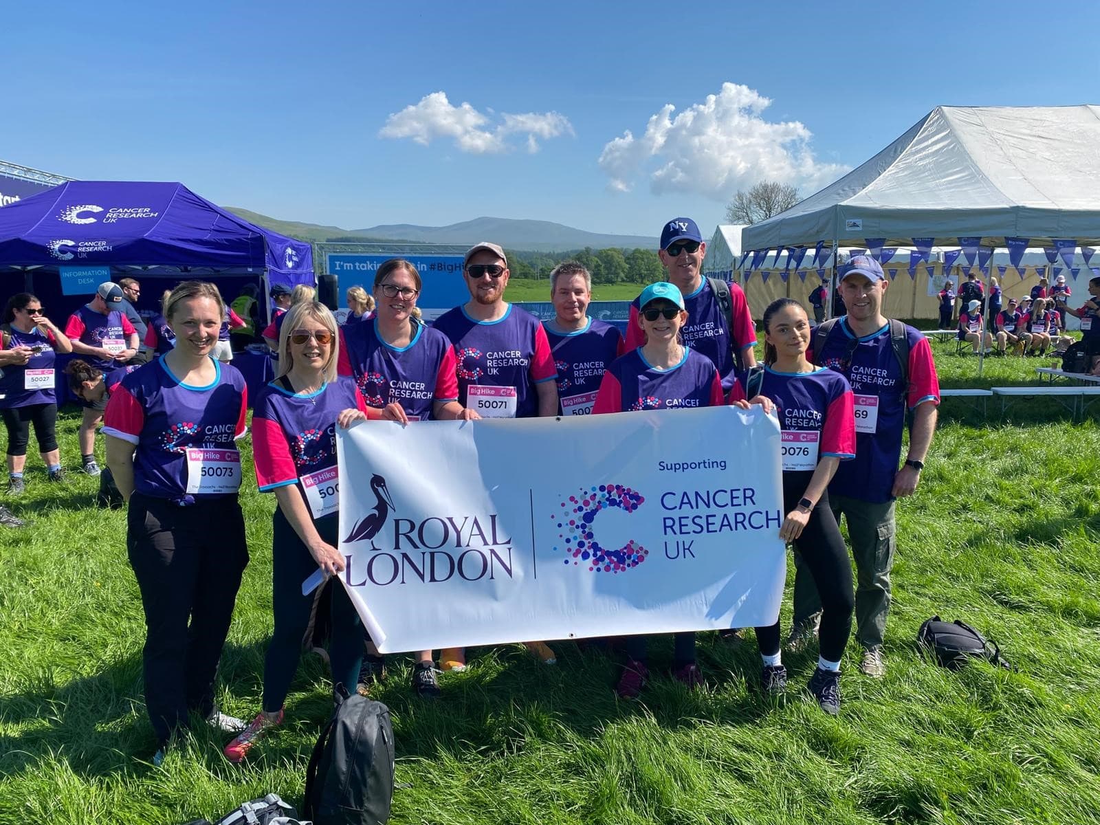 A group of people from Royal London holding a Cancer Research UK banner at a Big Hike event.