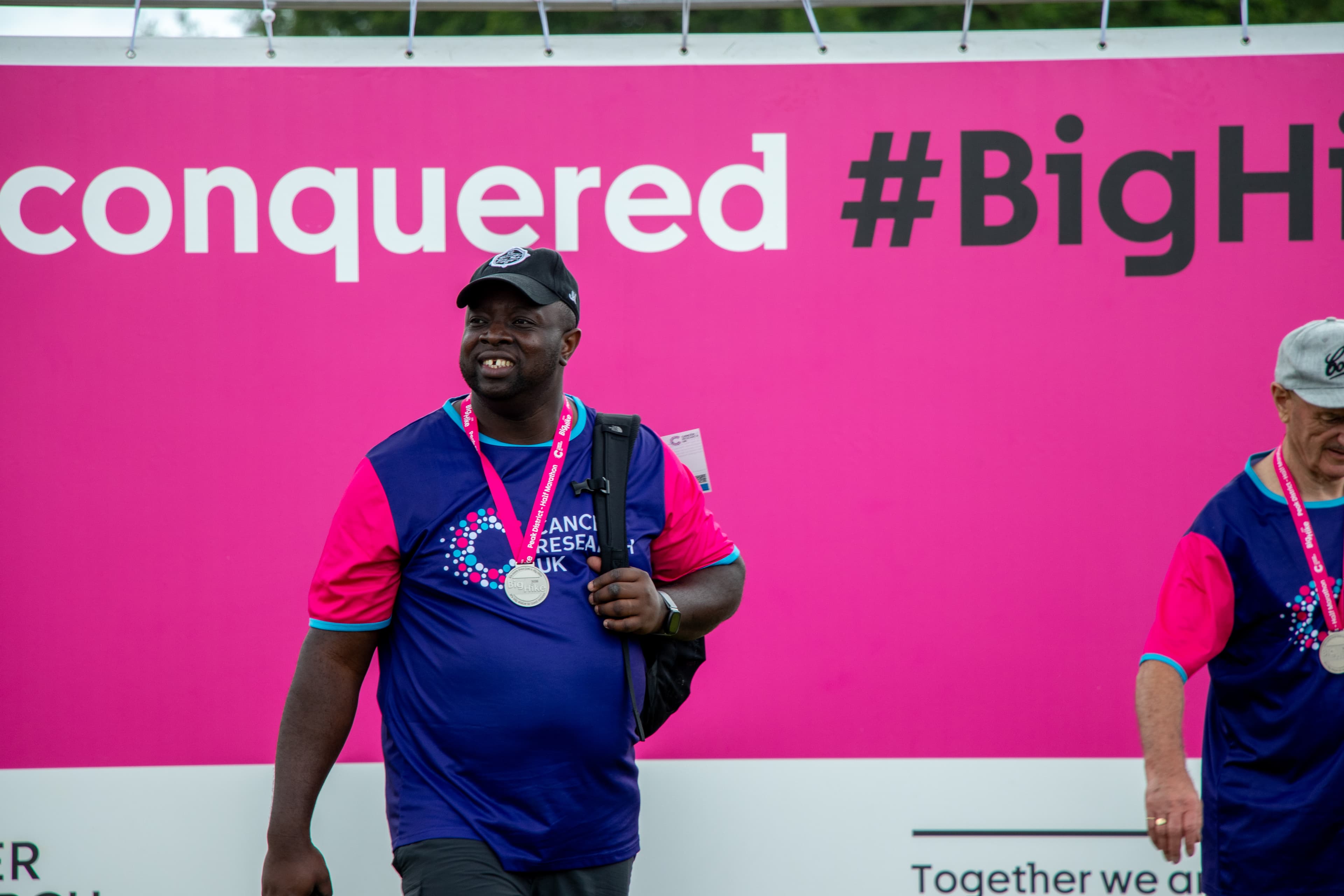 A man with his Big Hike medal smiling.