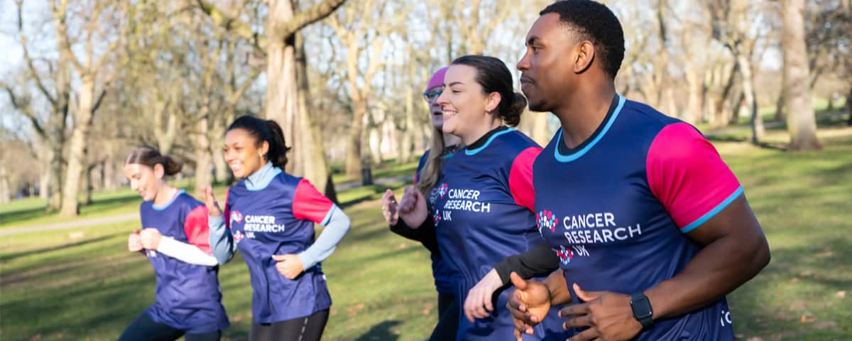 Group of people with CRUK T-shirts doing sports in a park.